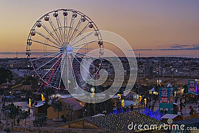 Festival Ferris wheel against sunset pink sky and urban scenery of Malta. Christmas market in La Valette during Editorial Stock Photo