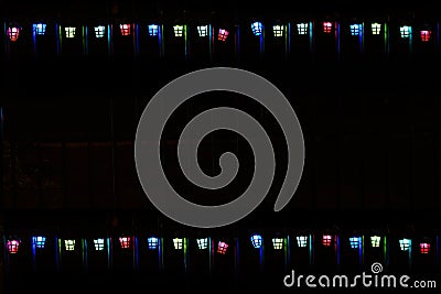 Festive background with two strings of coloutful lantern-shaped Chirstmas ights framing the black. Defocused Stock Photo