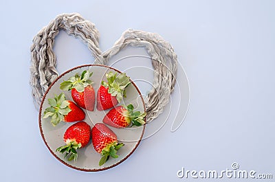 Festive blue background. Red paper hearts and fresh strawberries on a plate. Love. Valentine`s Day. Food backgrounds. Stock Photo