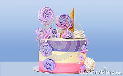 Festive cake with colored stripes of pink and purple decorated with multicolored marshmallows on a blue background for decoration Stock Photo