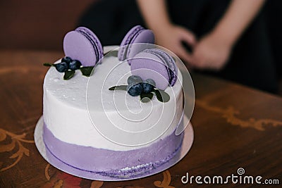 A festive cake in lilac style decorated with cakes, macaroni cookies with filling, fruits and berries on the cake Stock Photo