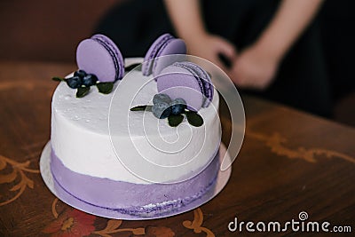 A festive cake in lilac style decorated with cakes, macaroni cookies with filling, fruits and berries on the cake Stock Photo