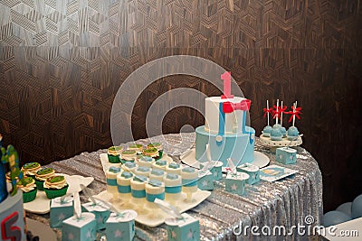 Festive candy bar for one year old boy birthday party. Cake with red number 1 and butterfly bow on shirt. Blue cakepops, cupcakes Editorial Stock Photo