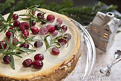 Festive cheese cake with raspberries, rosemary and lingonberries on the background of a fir branch and a toy house Stock Photo