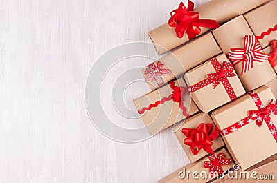 Festive craft paper gifts with red bows closeup on soft white wood board, top view, border. Stock Photo