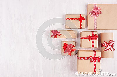 Festive craft paper gifts with red bows on soft white wood board, top view, border. Stock Photo