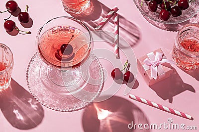 Festive flat lay with cherries drinks and a gift box, all in pink color Stock Photo