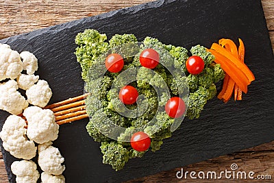 Festive food: a healthy Christmas tree of fresh broccoli, cauliflower, tomatoes, pepper closeup. Horizontal top view Stock Photo