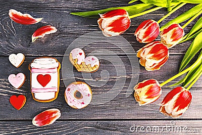 Festive gift gingerbread for Valentine's Day in the shape of a cup of coffee, hearts and a donut and a bouquet of red tulips Stock Photo