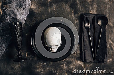 Festive Halloween table setting in a black style. Plate with fork, spoon and knife on a linen napkin. Halloween dinner. Minimal Stock Photo
