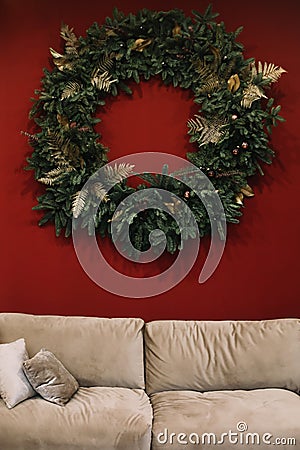 Festive home interior design concept. Christmas wreath on the wall in the living room. Christmas and New Year celebration decorat Stock Photo