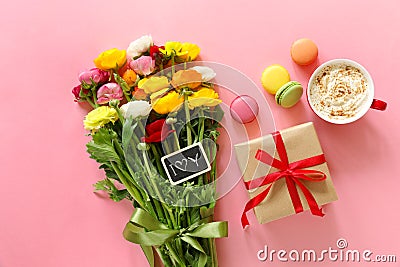 Festive morning concept buttercup flowers bouquet, gift box, cup of cappuccino and makarons cake on the pink background. Stock Photo