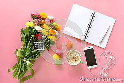Festive morning concept buttercup flowers with note good morning, cup of cappuccino, cake makaron, mobile with headphones, noteboo Stock Photo