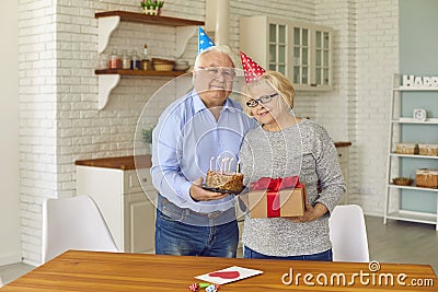 Loving older man congratulated his wife on the anniversary by giving her a gift and cake. Stock Photo