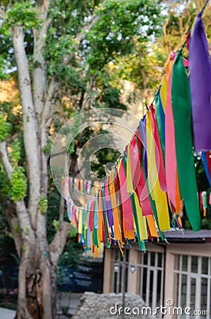 Festive multi-colored satin ribbons decorate the street. Bright ribbons hang in a row in the park. Selective focus Stock Photo