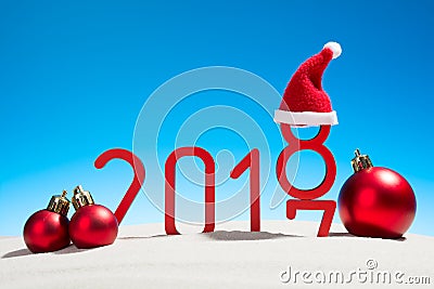 Festive New Years concept with Christmas balls a sunny tropical beach with the changing date 2017 - 2018 in red and copy space on Stock Photo