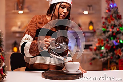 Festive person wearing winter sweater pouring cup of tea Stock Photo
