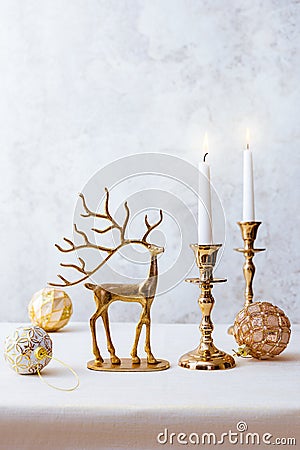 Festive still life with burning candles, figure of deer and Christmas decorations on pastel light background. Christmas Stock Photo