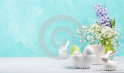 Still life of Easter small white ceramic bunnies, decorative eggs, jacinth and gypsophila flowers. Stock Photo