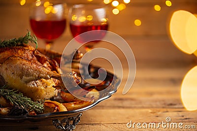 The festive thanksgiving dinner with traditional turkey on the plate and two glasses red wine isolated on wooden background with Stock Photo