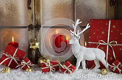 Festively christmas decoration with red gifts and a white reindeer in the snow. Stock Photo