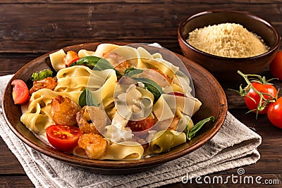 Fettuccine pasta with shrimp and tomatoes on old table Stock Photo