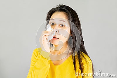 Fever,Young Asian woman wearing yellow shirt,Have a cold, wipe the snot on gray background,health care concept Stock Photo