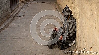 Anonymous poor beggar in the street of Fez, Morocco. Editorial Stock Photo