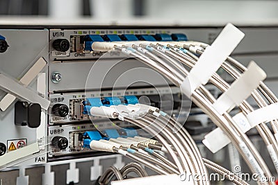 Fiber optic cables with a kink protection metal braid with white tags are connected to the device. Horizontal Stock Photo