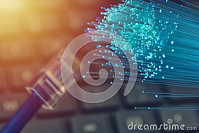 Fiber optics in blue, close up with ethernet and keyboard background, warm lens flare Stock Photo