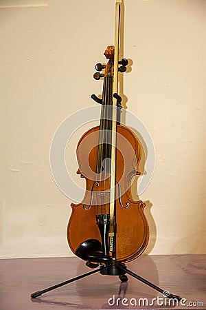 Fiddle and bow on it`s stand on a pink background. Stock Photo