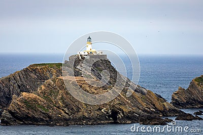 Fidra Lighthouse on top of a cliff in the United Kingdom with the sea and horizon in background Stock Photo