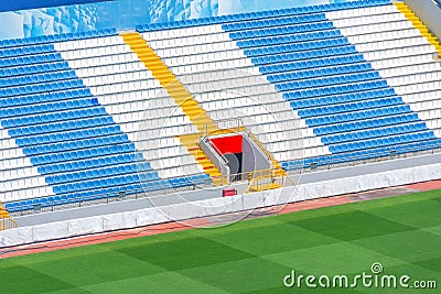 Field of empty white and blue seats, yellow stairs, gate exit on the stadium corner Stock Photo