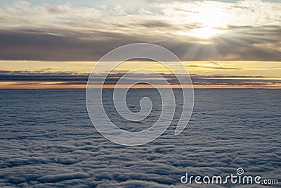 Field of fluffy clouds below going to the horizon. From above through clouds are rays of . Picture from the window of the aircraft Stock Photo