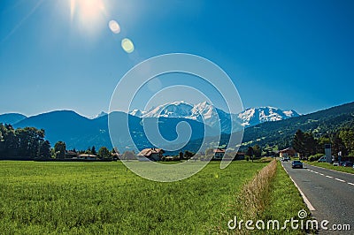 Fields with houses and road, forest, alpine landscape and blue sky in Saint-Gervais-Les-Bains Stock Photo