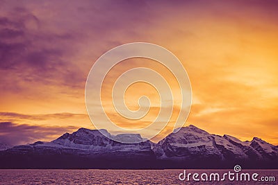 A fiery dawn over the snowy peaks of the fjord Stock Photo