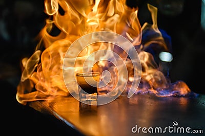 Fiery show at the bar. The bartender makes hot alcoholic cocktail and ignites bar. Fire on bar. glass with an alcoholic drink on Stock Photo