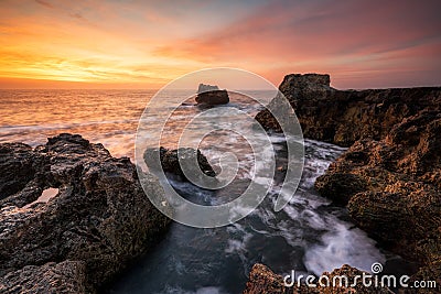 Fiery sunrise sky at a rocky coastline Stock Photo