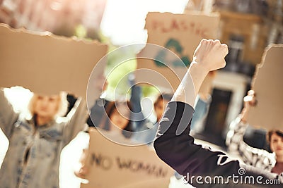 Fight like a girl Back view of female activist protesting for ecology with group of demonstrators holding signboards Stock Photo