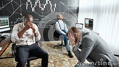 Fight together. Three traders sitting by desks in front of computer monitors while working in the office. They are Stock Photo