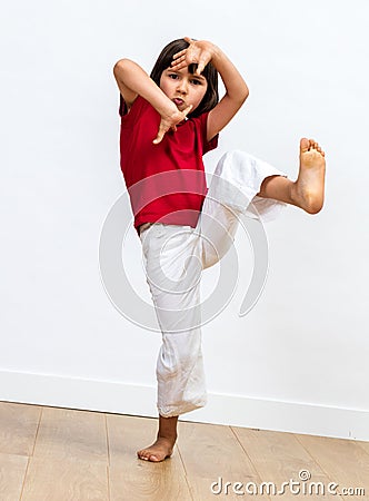 Fighting child raising feet and playing hands to practise taekwondo Stock Photo