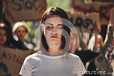 Fighting for clean planet. Young activist with word freedom written on her face keeping eyes closed while protesting Stock Photo