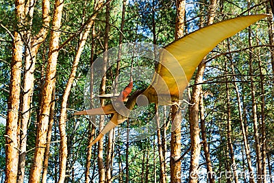 The figure of a dinosaur hovering under the trees in the forest. Stock Photo