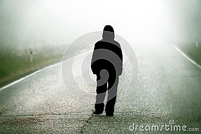 Figure of a man walking on a foggy road Stock Photo