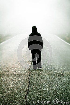 Figure of a man walking on a foggy road Stock Photo