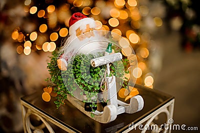 Figure of santa claus on sleigh with green plant stands on table against blurred background Stock Photo