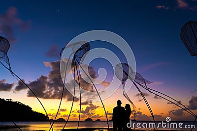 Figures of jellyfish on a background of a beautiful sunset. Couple hugs on a background of a fiery sunset. Tropical romance. Beach Stock Photo