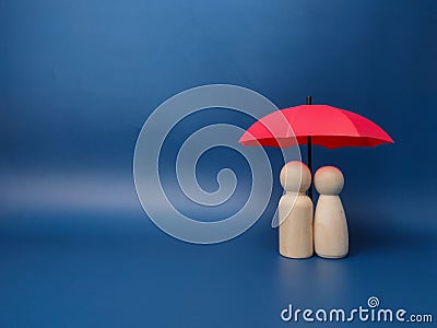 Figures standing beneath a red umbrella on a blue background Stock Photo