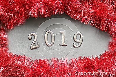 Figures 2019 on a wooden background, around the frame of Christmas tinsel red. Stock Photo