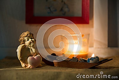 Figurine little angel with a heart who dreams of burning candle Stock Photo